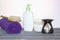White plastic jars with creams, purple towel, candle, brush for dry massage. The concept of Spa, body care