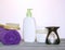 White plastic jars with creams, purple towel, candle, brush for dry massage. The concept of Spa, body care