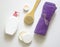 White plastic jars with creams, purple towel, candle, brush for dry massage. The concept of Spa, body care. Top view