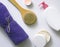 White plastic jars with creams, purple towel, candle, brush for dry massage. The concept of Spa, body care. Top view.