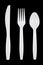 White plastic knife, fork and spoon on black background.