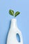 White plastic packaging of laundry detergent, liquid powder, washing conditioner, green leaves on blue background. Flat lay top