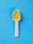 White plastic spoon with fish oil capsules on a blue background. Biologically active additive