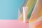 White plastic tube for beauty product on blue pink background with colorful rainbow organza fishnets fabric drapery