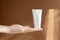 White plastic unmarked tube for cream on woman's palm in rays of sunlight. Container for professional cosmetic