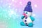 White plasticine snowman with purple winter hat, pink nose, playdough or modeling compound dough, blurred christmas neon