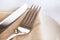 White plate with beige napkin, fork and knife