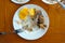 On a white plate are the bones of an eaten fried fish and slices of lemon skin.
