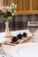 White plate with chocolate desserts with a glass of water served on the table with a vase of flowers