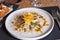 White plate with Cod Carpaccio with chili vinaigrette, pumpkin seeds and chips