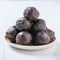 White plate filled with homemade chocolates of dried fruit and chocolate on a white wooden table