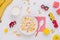 White plate with flakes, banana, dried apricots and milk with wooden toys