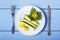 White plate with freshly sliced cucumbers, green leaves and yellow flowers. Healthy food from natural organic vegetables. Fork and