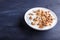 White plate with greek yogurt, granola, almond, cashew, walnuts  on black wooden background