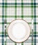 White plate on green checkered tablecloth