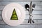 White plate on grunge wooden background with xmas tree and silverware. Xmas card. Happy New Year. Space for text. Top view.