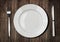 White plate, knife and fork on old wooden table