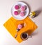 White plate with muffins, cakes, coffee mug and a bouquet of wildflowers