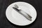 White plate with parallel knife, spoon on dark