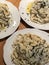 White plate with pasta with cream sauce and truffles on the table