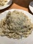 White plate with pasta with cream sauce and truffles on the table