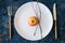 White plate, red apple, cutlery and tree brunches on a blue stone background. Autumn, Thanksgiving, Halloween concept.