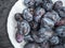 White plate with ripe prunes on a dark wooden background