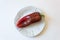 White plate with ripe red Capsicum annuum Cubanelle pepper, Cuban pepper, Italian frying pepper
