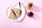 White plate in shape of heart with sandwiches with peanut butter and strawberry jelly on pink background. Top view