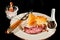 white plate of sliced, rare, roast beef, chunks of cheddar cheese a cheese knife and containers of sea salt and pepper corns