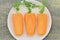 White plate with slices carrots and herbs on wooden table