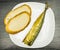 White plate with smoked mackerel with a golden skin and slices of bread.