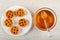 White plate with soft waffle, honey dipper in transparent bowl with liquid honey on wooden table. Top view