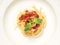White plate, spaghetti top view, with red tomato sauce and green basil leaves on top