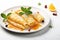 A white plate topped with crepes covered in syrup. Classic Crepe Suzette