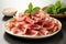 A white plate topped with slices of ham next to a bowl of basil