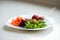 A white plate with vegetables, chard sprouts and garden strawberries strung on chopsticks. Selective focus