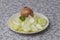 White plate on which is peeled onion decorated with parsley and as decoration is whole unpeeled onion