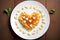 On a white plate with a wood background, heart shaped pasta is topped with tomato sauce and parmesan cheese