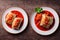 White plates with portion of stuffed cabbage rolls in bright tomato sauce