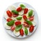 White platter of sliced mozzarella, cherry tomatoes and basil le