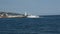 A white pleasure boat returns to the pier, passing by the lighthouse