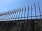 White pointed iron fence, concrete wall, sunlight