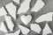 White polystyrene heart on a gray background, surrounded by fragments of polystyrene. Shards of a heart, a broken heart