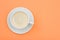 White porcelain cup of black coffee on saucer on peach color background