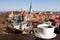 White porcelain cup of coffee or tea with view from above of red rooftops, historic old town and churches in Tallinn