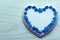 White porcelain heart and light flowers laid out in the shape of a heart on a blue wooden table