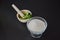 A white porcelain mortar and pestle, fresh green mint leaves, glass cup full of sugar, black background