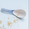 White porcelain spoon decorated with blue oriental motifs with scattered sesame seeds on blue background