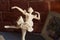 White porcelain statuette of a ballerina against a brick wall background